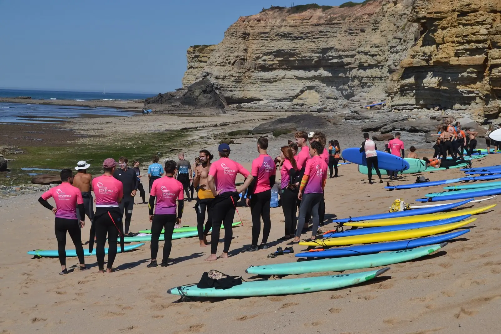 A large group of surfers gathered on the beach in Ericeira
